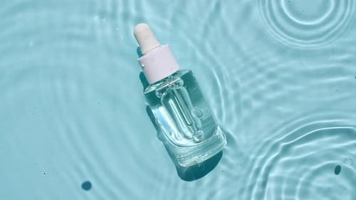 Clear Serum Bottle on Blue Water Background