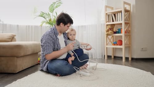 Father and Infant Playing With Power Strip Indoors