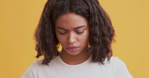 Woman scowling in close up on yellow background
