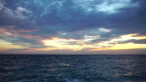 Dramatic Seascape Over the Beach During Sunset with Rocky Volcanic Cliff is Lit By the Warm Sunset