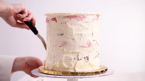 Hands decorating delicious layered cake with white frosting