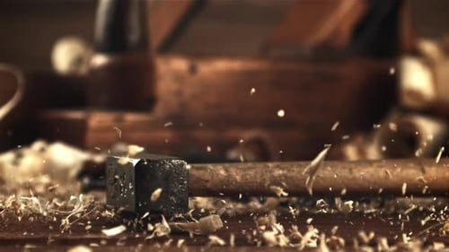 A Hammer Falls on a Table with Wooden Sawdust