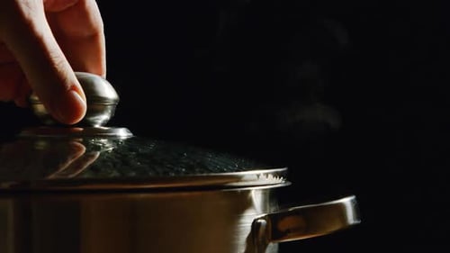 Human Hand Lifts Up A Cover Of A Pan - A Stream Breaks Out