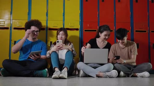 Happy group of student friends use digital tablet, smartphone, computer laptop in in college.