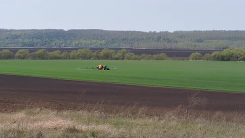 Tractor Sprays Crops in Rural Green Field