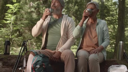 Aged Hikers Drinking Tea from Thermos Bottle