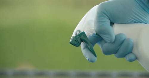 Hand Wearing Gloves Squeezing Spray Bottle