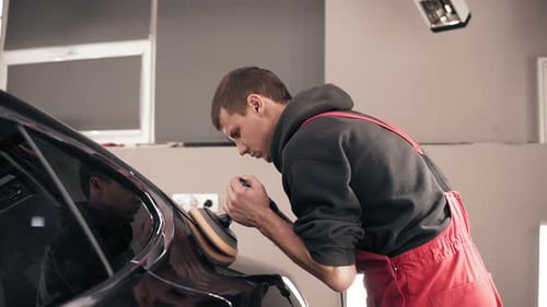 Man Polishing Black Car in Auto Body Shop