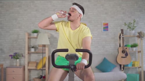 Man with Moustache Exercising on Stationary Bike at Home