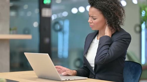 Young Adult Woman Massaging Neck at Desk