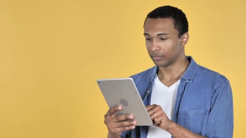 Young Adult Using Tablet on Yellow Background