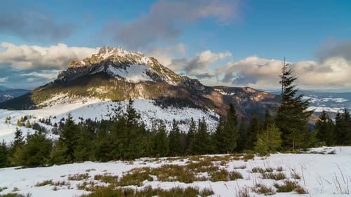 Colorful Sunny Winter Morning in Snowy Mountain with Clouds Flying over Peak