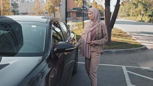 Mujer en hiyab subiéndose al coche