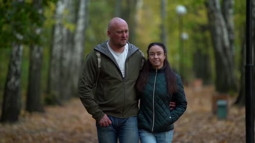 Liebevoller Ehemann und Ehefrau umarmen sich und gehen in der malerischen Gasse im Herbstpark spazieren, Medium