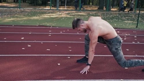 Shirtless athlete starts running on the stadium.