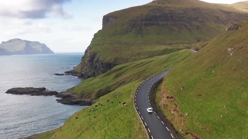 Car Driving Along Coastal Road View on Wild Green Island. Faroe Island Road Along Beautiful Coast