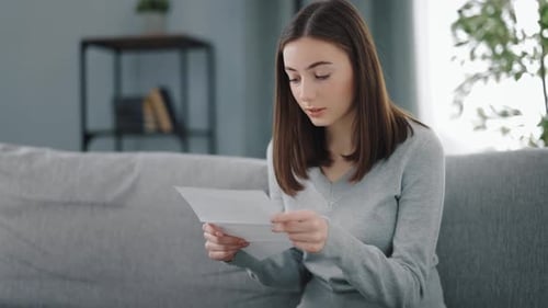 Woman Reading Letter on Sofa Indoors