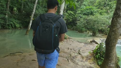 Man Walks Near Tropical Waterfall