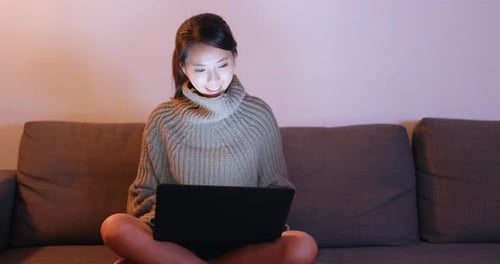 Woman Uses Laptop on Couch at Night