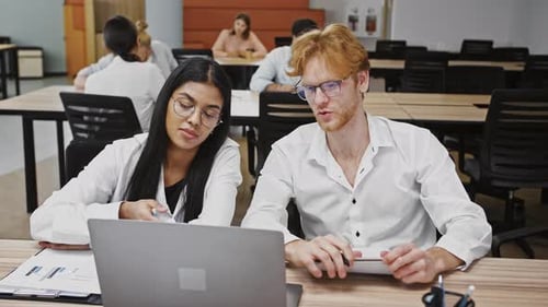 Divers jeunes collègues travaillant sur un ordinateur portable discutant d'idées créatives pour développer un projet de conception