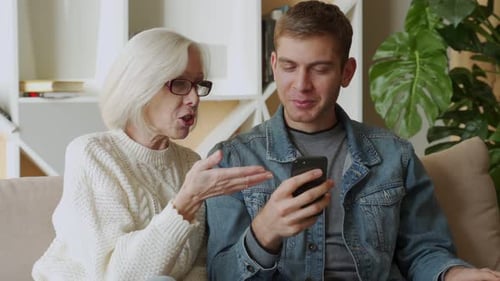 Senior Woman and Adult Man Using Smartphone Together