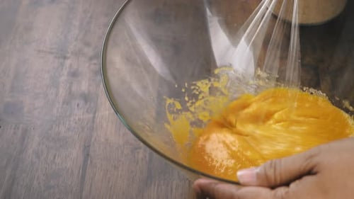 Mezcla de yema de huevo y azúcar que se revuelve en un recipiente de vidrio para cocinar el ponche de huevo