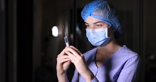 Health Care Worker Inspects Syringe in Close Up