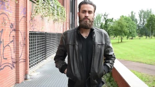 Man With Beard Walks Toward Camera in Urban Park
