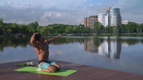 Muscular Man Stretching on Lake Dock