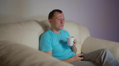 Man Relaxing on Couch Watching Television at Home