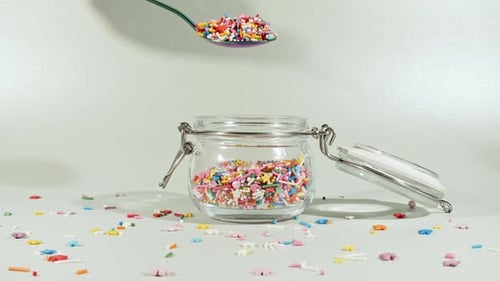 Colorful Candy Confectionery Run Poured Into a Jar Glass on Green Background