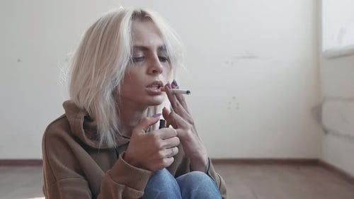 Young Woman Lights Cigarette While Sitting Indoors