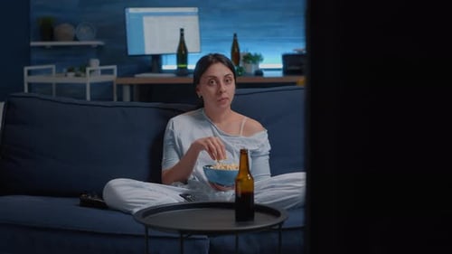 Concentrated Woman Eating Popcorn and Watching an Interesting Movie on Tv