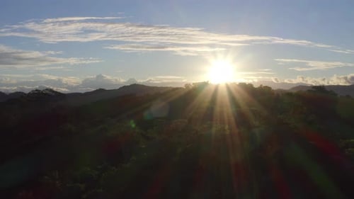 Pôr do sol acima de uma floresta tropical, mostrando os raios de sol brilhando sobre a copa das árvores