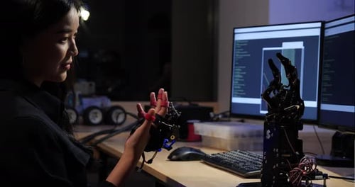 Asian girl developing software and testing robotic arm