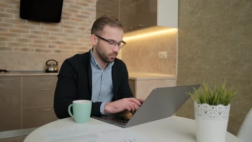 Man Working at Laptop in Kitchen Environment