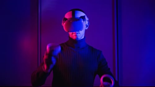 Man Using VR Headset with Controllers in Dark Room