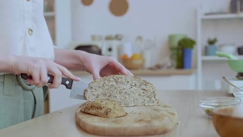 Woman Cuts Fresh Bread Loaf in Kitchen