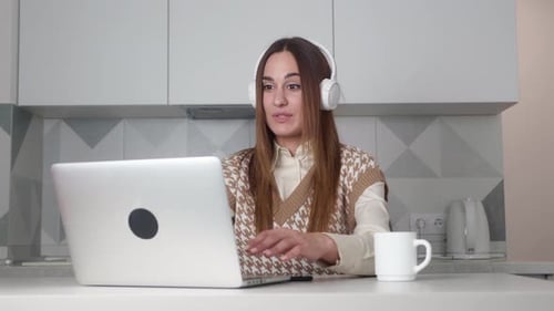 Young Woman Talking on Laptop in Modern Kitchen