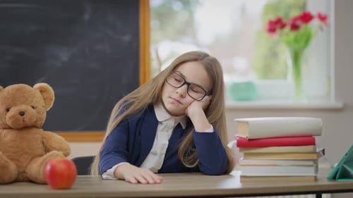 Bored Caucasian Schoolgirl Sitting at Desk Putting Head on Table Falling Asleep