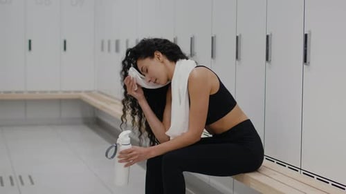 Woman Wipes Sweat After Workout in Locker Room
