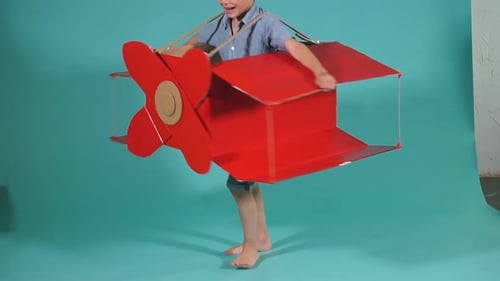 Smiling Child in Cardboard Airplane Costume