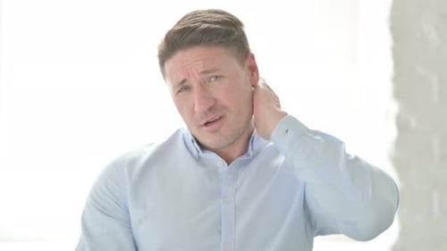 Man Rubbing Neck in Discomfort Indoors