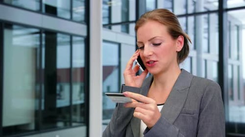Young Woman Talks on Phone and Holds Credit Card