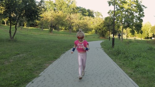 Kleines kaukasisches Läuferkind Mädchen in rosa Sportbekleidung läuft draußen im Park. Workout für Kinder