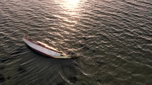 Dilapidated Boat in Peaceful Water at Sunset