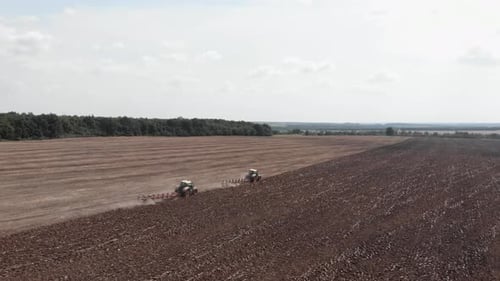Tractors Tilling Soil in a Brown Field, Aerial