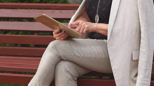 Business Woman in White Jacket Relaxes in Park Using Tablet