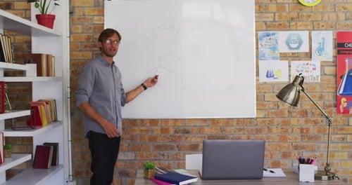 Caucasian male teacher teaching chemistry while looking at laptop in the classroom at school