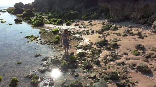 Woman Walks in the Beach Near to Rocks Seaweed